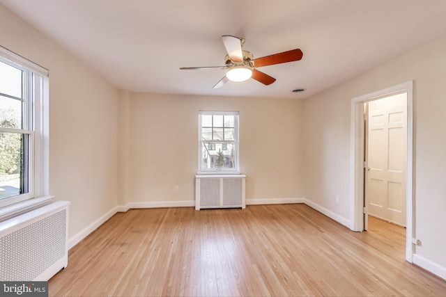 empty room with light wood-type flooring, radiator heating unit, visible vents, and baseboards