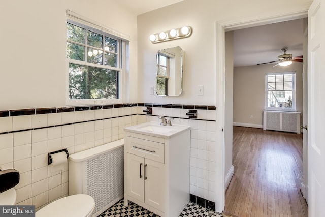 bathroom featuring radiator heating unit, vanity, toilet, and tile walls