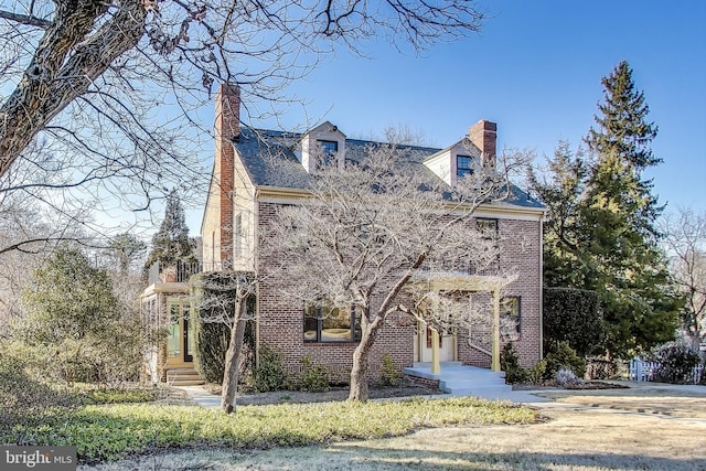 view of front of house with brick siding and a chimney