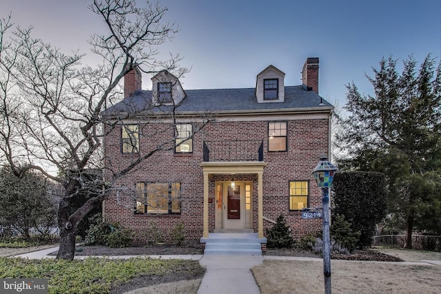 georgian-style home with brick siding and a chimney