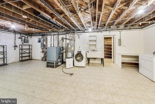 unfinished below grade area featuring a sink, water heater, electric panel, a heating unit, and washing machine and clothes dryer