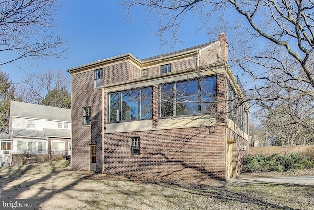 view of side of home featuring brick siding and a chimney