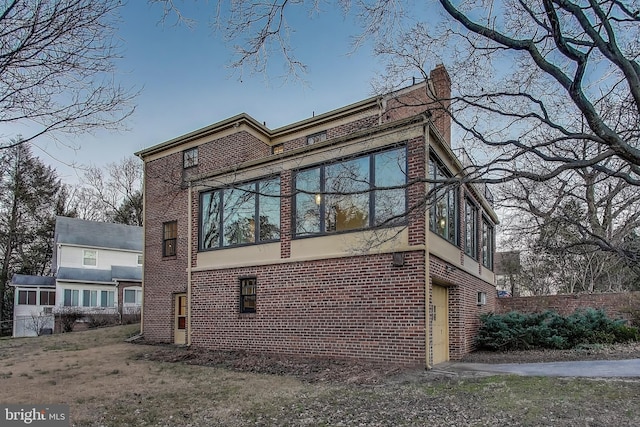 view of property exterior featuring brick siding and a chimney