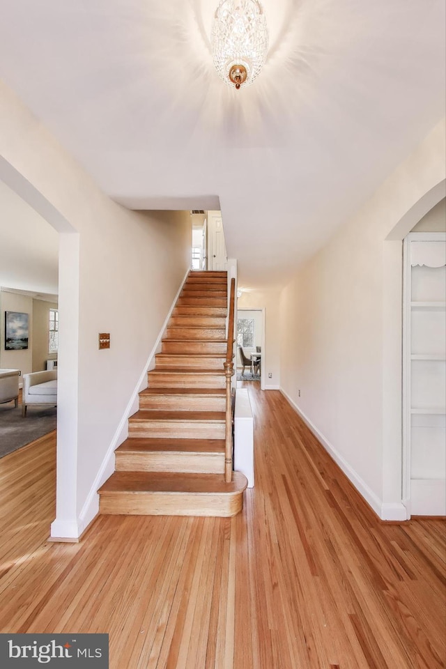 stairway featuring wood finished floors, a wealth of natural light, and baseboards