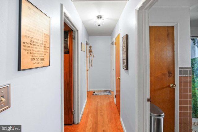 corridor featuring light wood-style flooring and baseboards