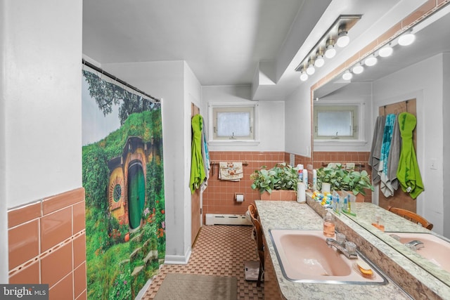 full bathroom with a wainscoted wall, tile walls, a shower with shower curtain, baseboard heating, and vanity