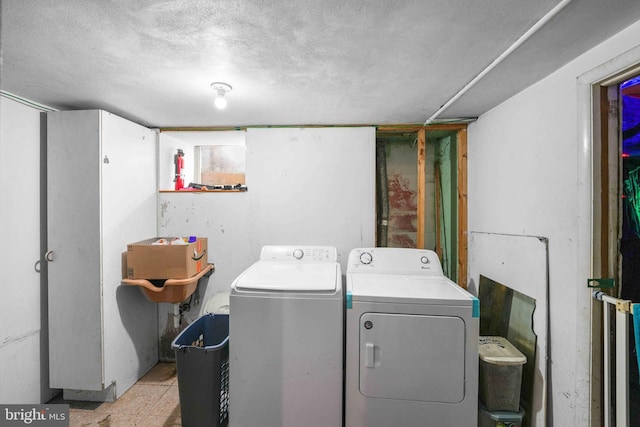 clothes washing area with laundry area, washer and clothes dryer, and a textured ceiling