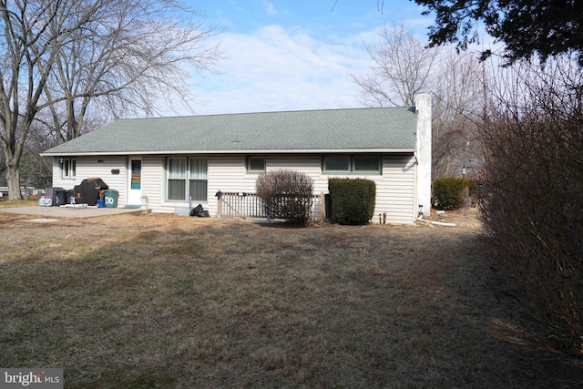 back of house with a lawn and roof with shingles