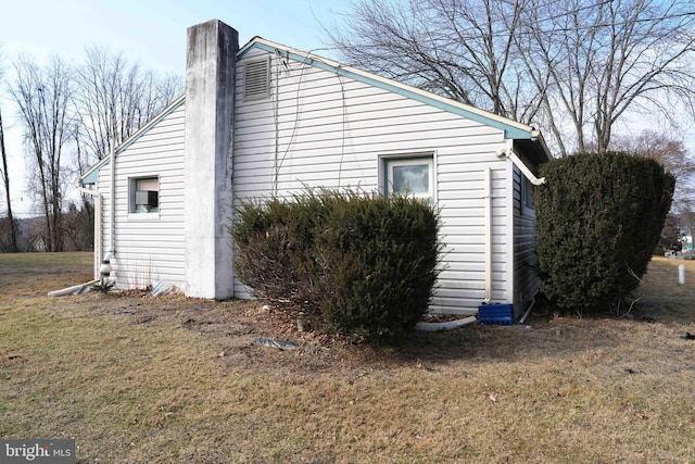 view of side of property featuring a yard and a chimney