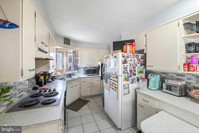 kitchen featuring light tile patterned floors, stainless steel appliances, light countertops, decorative backsplash, and under cabinet range hood