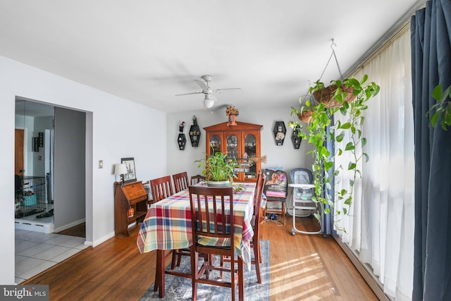 dining area with light wood-style flooring, baseboards, and a ceiling fan