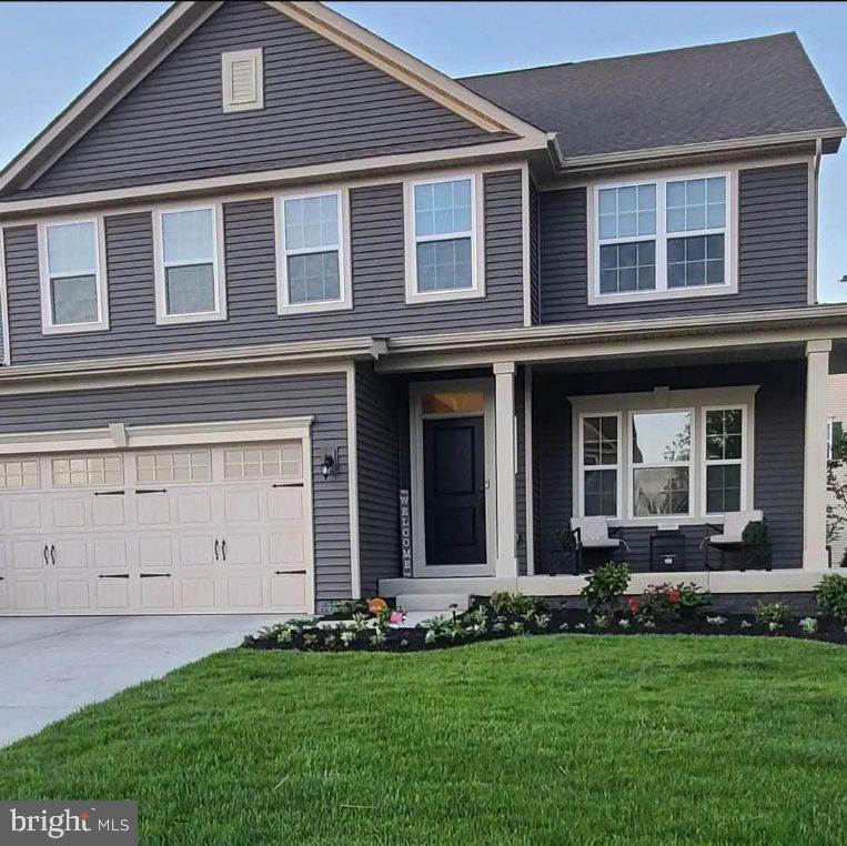 view of front of house featuring an attached garage, a porch, concrete driveway, and a front yard