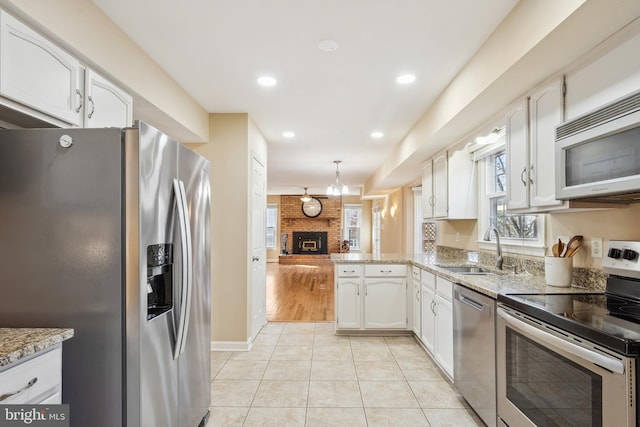 kitchen with white cabinets, light tile patterned floors, appliances with stainless steel finishes, and a sink