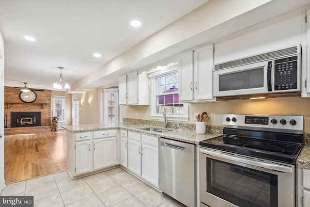 kitchen with light stone counters, light tile patterned floors, a sink, white cabinets, and appliances with stainless steel finishes