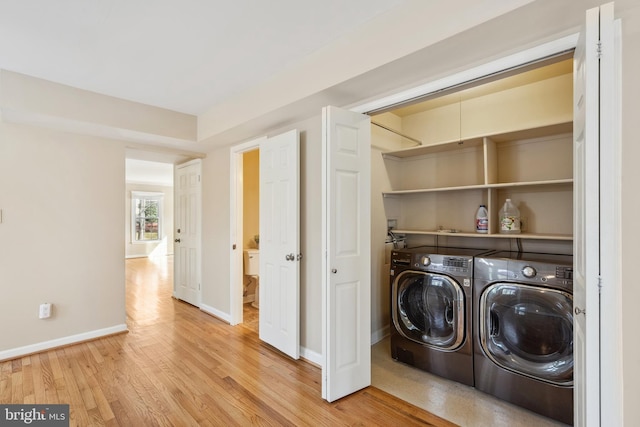 laundry room featuring laundry area, washing machine and dryer, light wood-style flooring, and baseboards