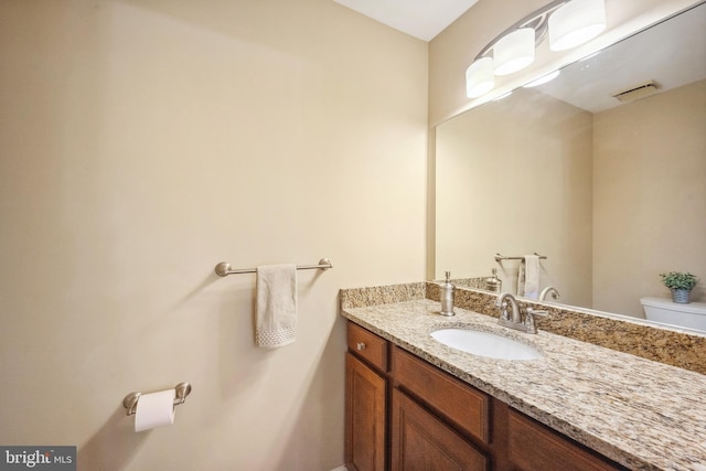 half bath with visible vents, toilet, and vanity