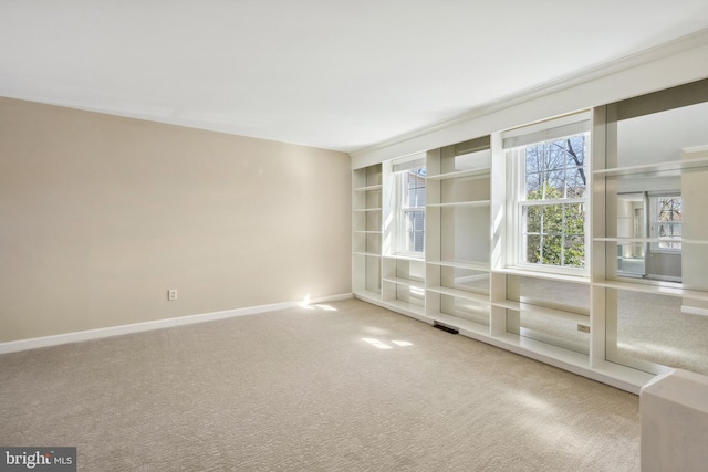 empty room with built in features, visible vents, baseboards, and carpet