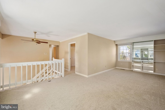 spare room with crown molding, carpet flooring, and baseboards