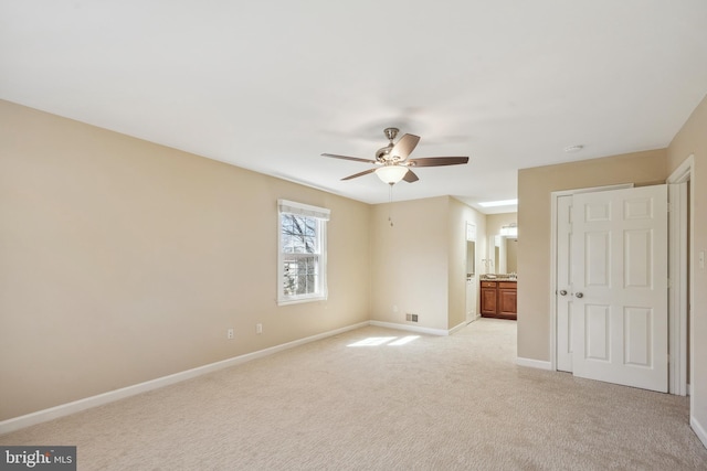 unfurnished bedroom with baseboards, light carpet, a ceiling fan, and ensuite bathroom