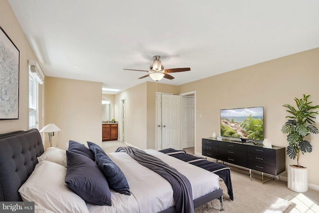 bedroom featuring ensuite bath, a ceiling fan, baseboards, and light carpet