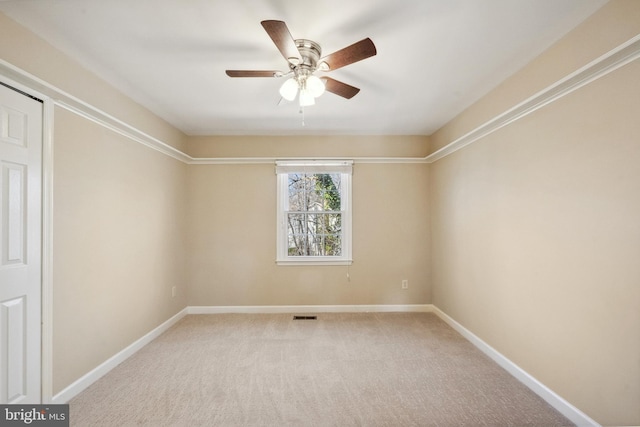 spare room featuring a ceiling fan, visible vents, baseboards, and light carpet