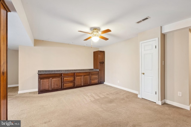 interior space featuring visible vents, light colored carpet, a ceiling fan, and baseboards