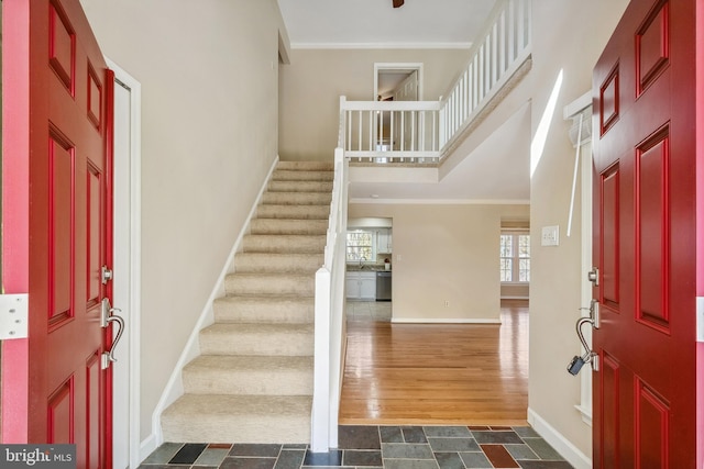 foyer entrance featuring stairway, baseboards, dark wood finished floors, ornamental molding, and a towering ceiling