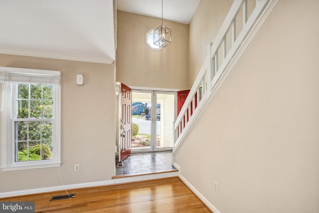 foyer with wood finished floors, baseboards, a high ceiling, stairs, and french doors