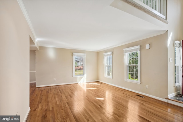 unfurnished room featuring visible vents, crown molding, baseboards, and wood finished floors