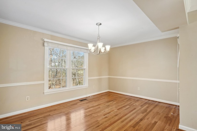 unfurnished dining area featuring an inviting chandelier, baseboards, light wood-style floors, and ornamental molding