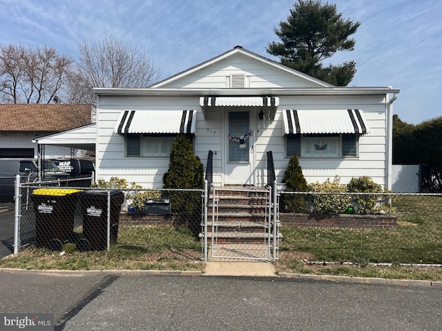 view of front facade with a fenced front yard, an attached carport, and a gate