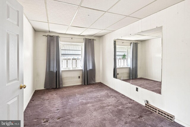 spare room featuring a paneled ceiling, carpet floors, and visible vents