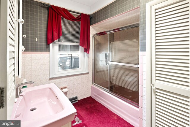 full bathroom with enclosed tub / shower combo, visible vents, tile walls, and a sink