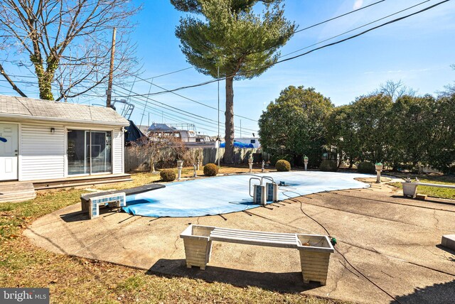 view of swimming pool featuring a covered pool, a patio, an outbuilding, and fence