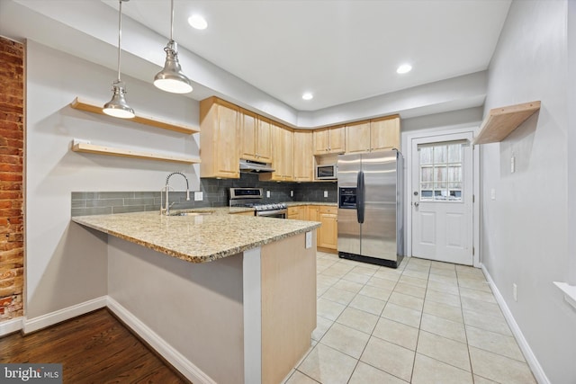 kitchen featuring light brown cabinets, stainless steel appliances, a peninsula, and a sink