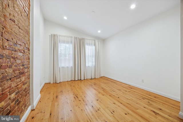 empty room featuring recessed lighting, light wood-style flooring, baseboards, and vaulted ceiling