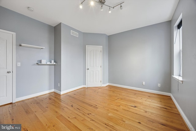 unfurnished bedroom with hardwood / wood-style floors, multiple windows, baseboards, and visible vents