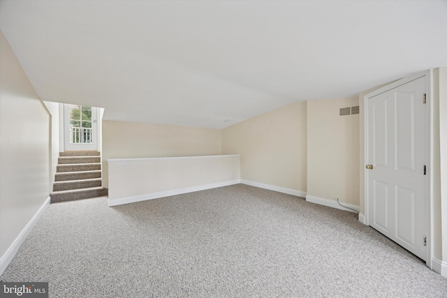 additional living space with baseboards, visible vents, and carpet floors