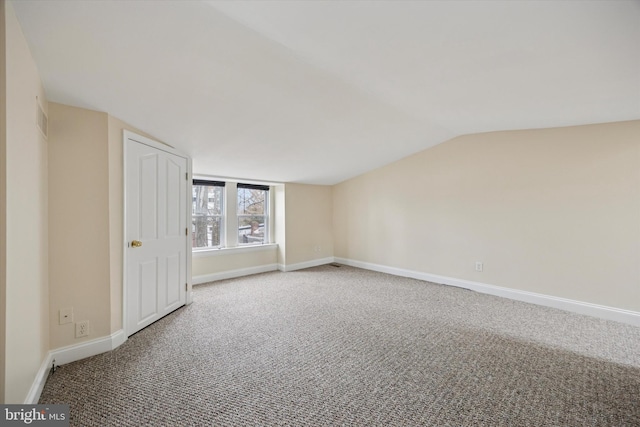 interior space featuring carpet flooring, visible vents, baseboards, and lofted ceiling