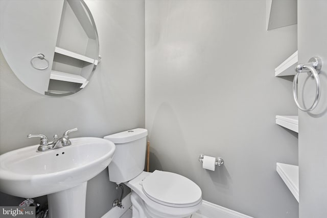 bathroom featuring toilet, baseboards, and a sink