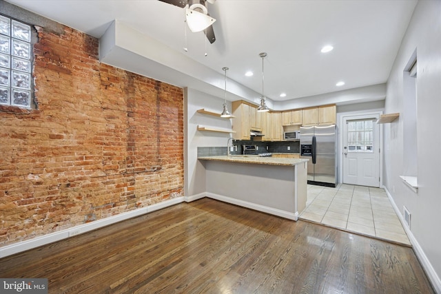 kitchen featuring light brown cabinets, open shelves, light wood-style floors, appliances with stainless steel finishes, and a peninsula