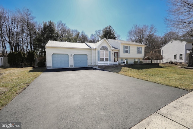 tri-level home featuring a garage, aphalt driveway, and a front yard