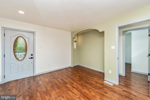 foyer with baseboards, visible vents, arched walkways, wood finished floors, and recessed lighting