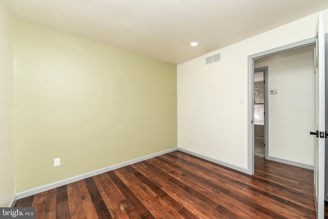 empty room featuring recessed lighting, dark wood-style flooring, visible vents, and baseboards