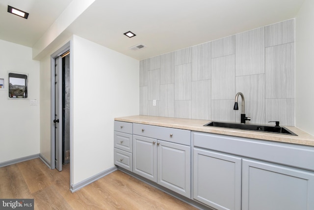 bathroom with wood finished floors, a sink, visible vents, and baseboards