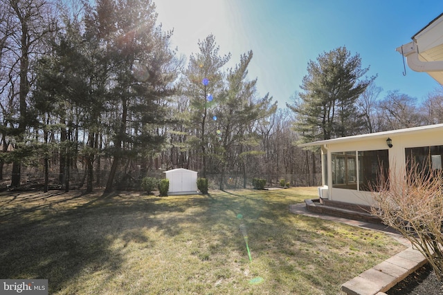 view of yard featuring an outbuilding, a sunroom, fence, and a storage unit