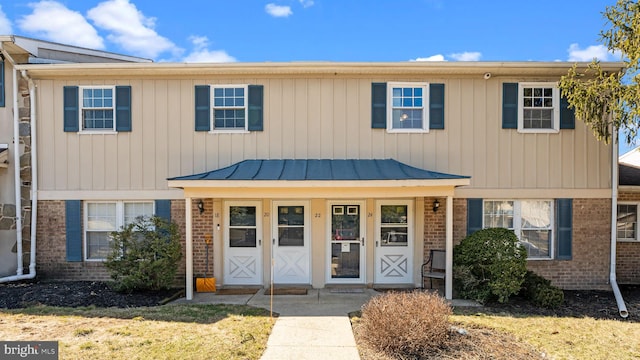 multi unit property featuring a standing seam roof, brick siding, and metal roof