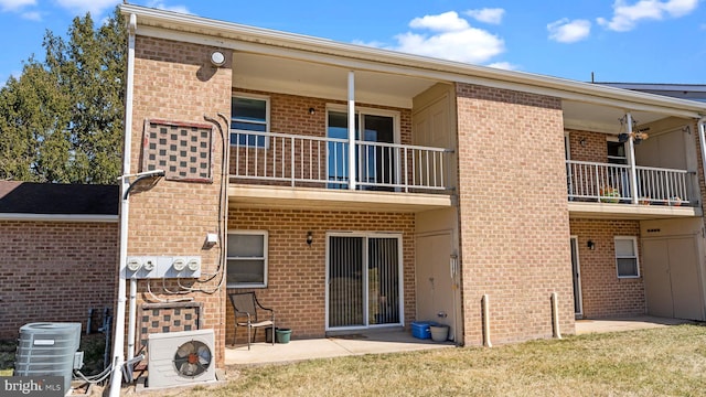 back of house with brick siding, central AC unit, and a balcony