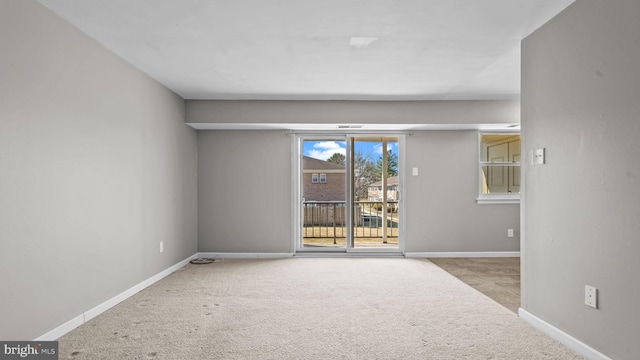 carpeted empty room featuring baseboards