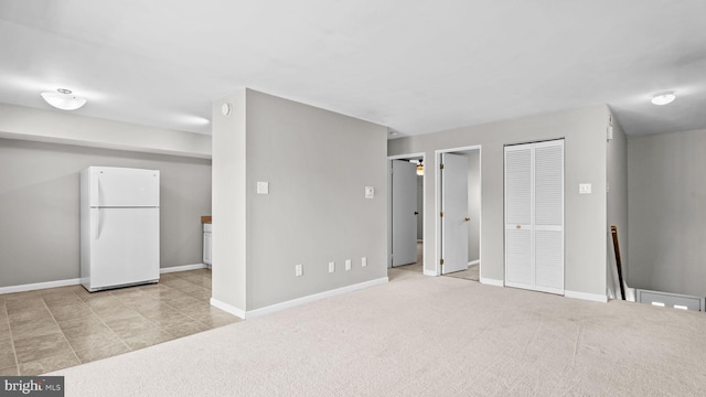 interior space with multiple closets, baseboards, freestanding refrigerator, and light carpet